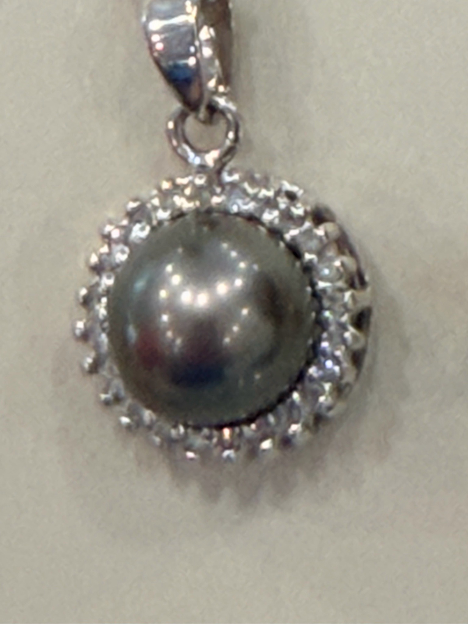 Submitted photo of Pendant with dark spherical gemstone or pearl in the style of a modern halo design