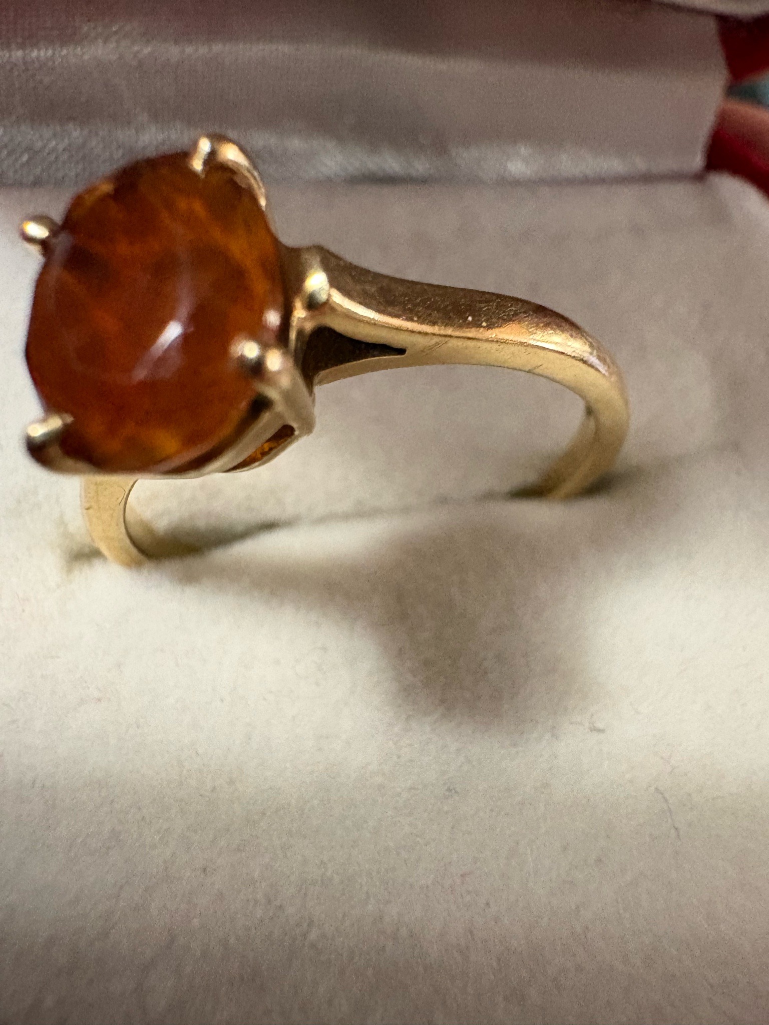 Submitted photo of Gold-tone solitaire ring featuring a faceted orange gemstone