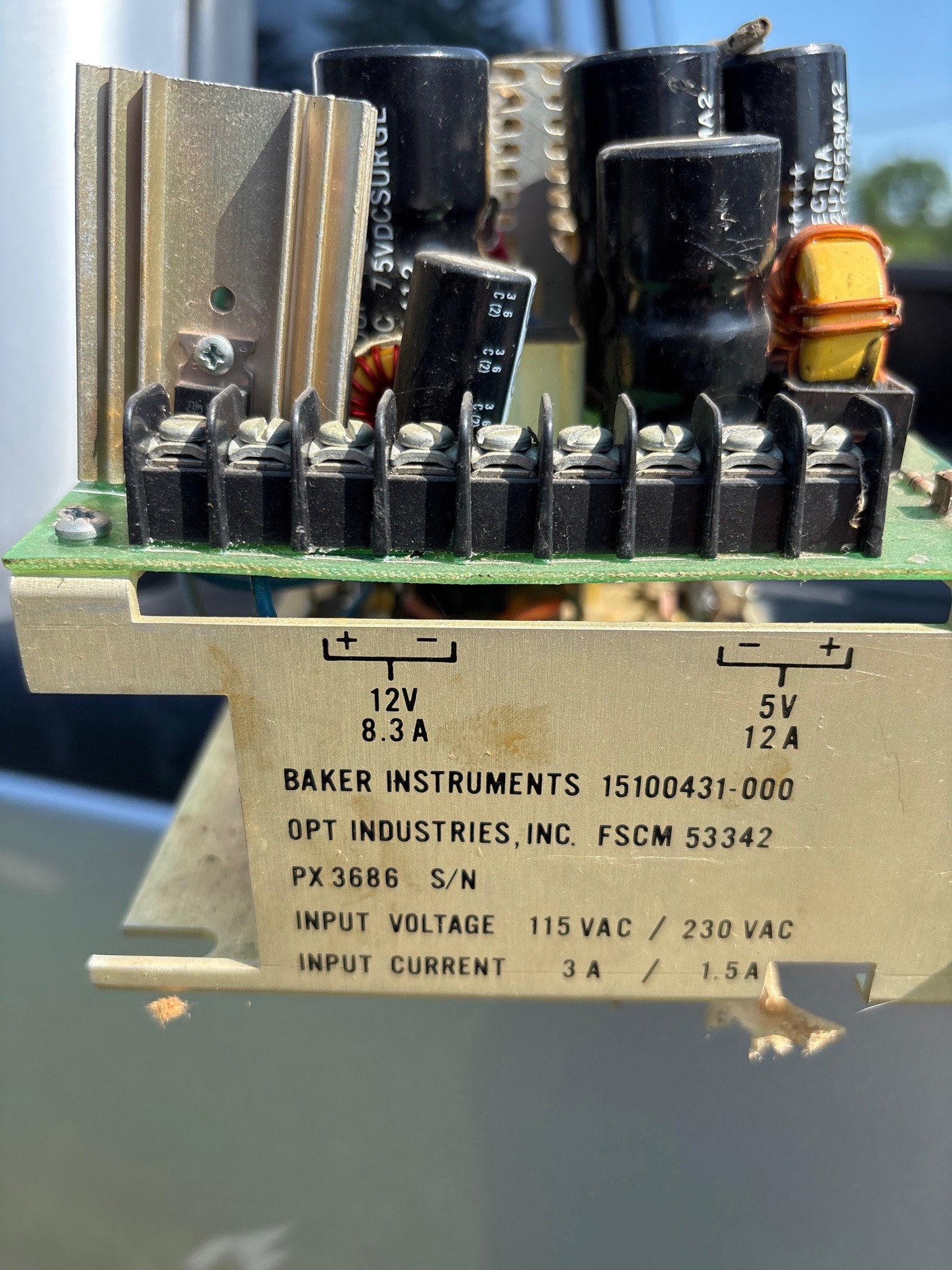 Submitted photo of Power supply assembly with metallic chassis and printed circuit board, labeled Baker Instruments