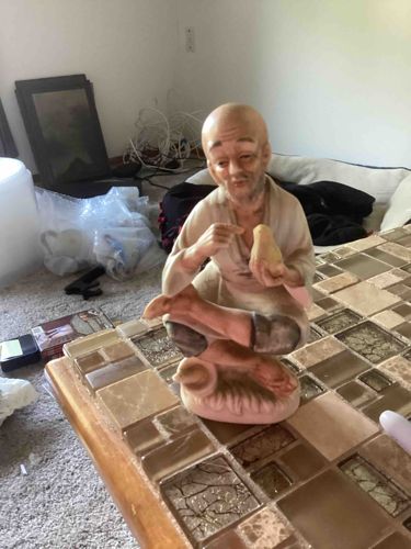 Elderly Man Holding Chick Figurine