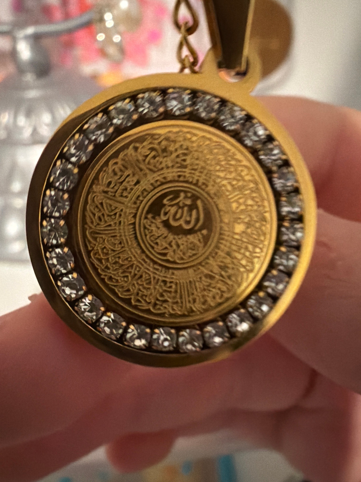 Submitted photo of Gold-toned metal and crystal pendant with Arabic calligraphy
