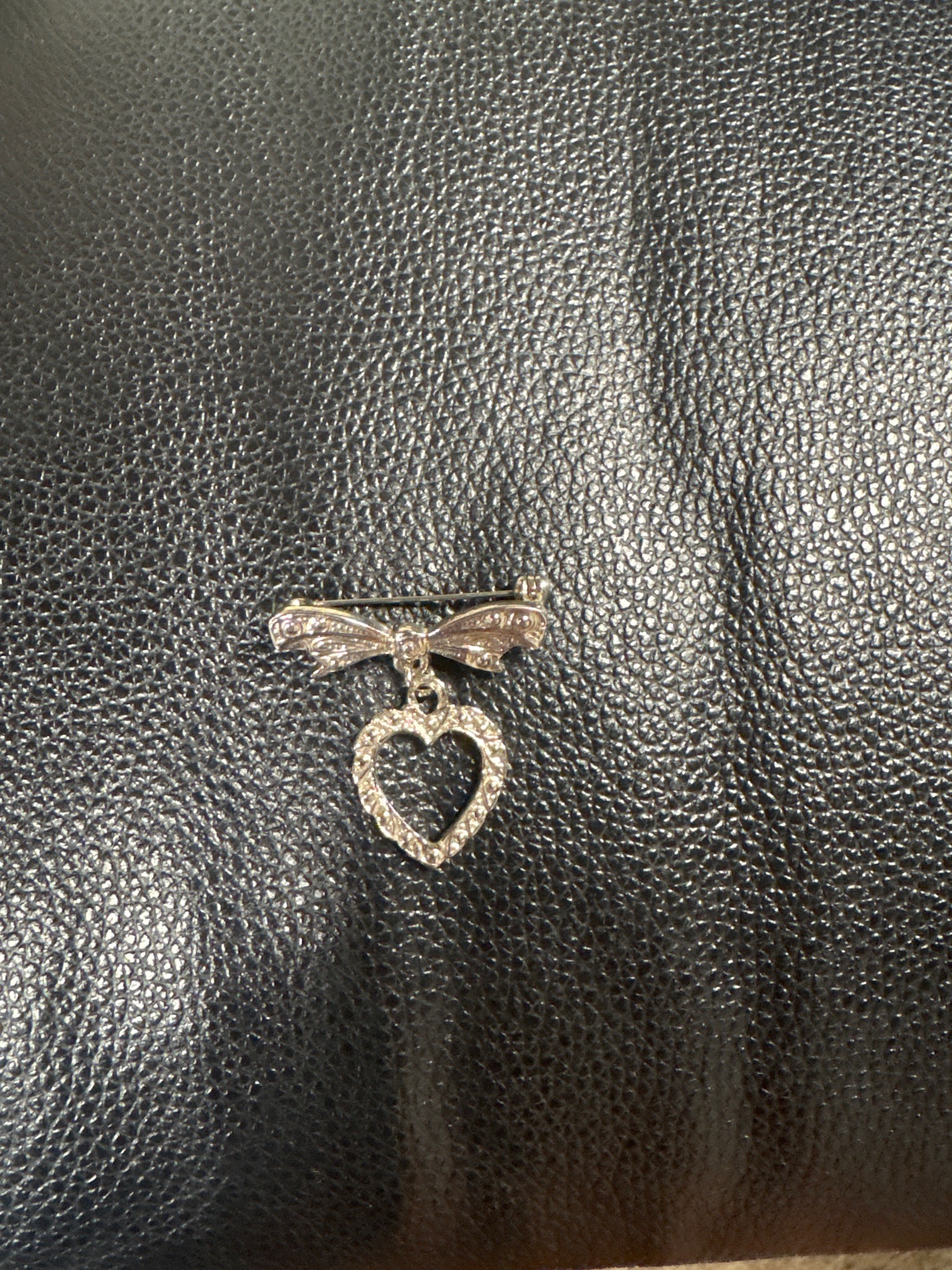 Submitted photo of Silver-tone metal and rhinestone bow and heart brooch