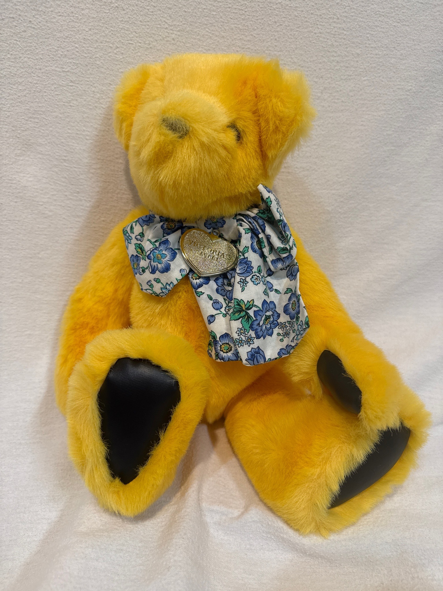 Submitted photo of Plush yellow teddy bear with floral bow and heart pendant (not authenticated)