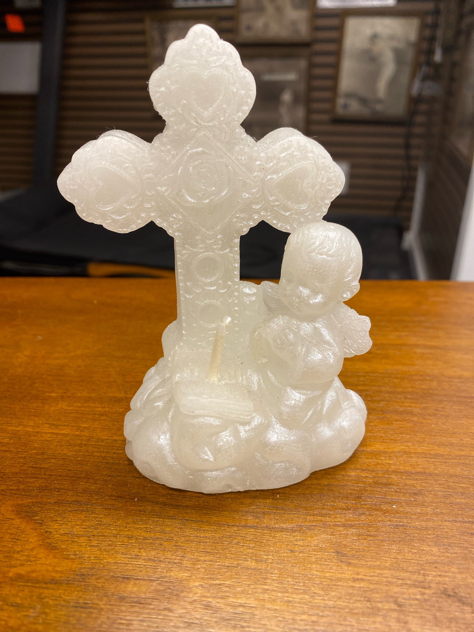 Submitted photo of Molded decorative wax candle featuring a cross and kneeling cherub