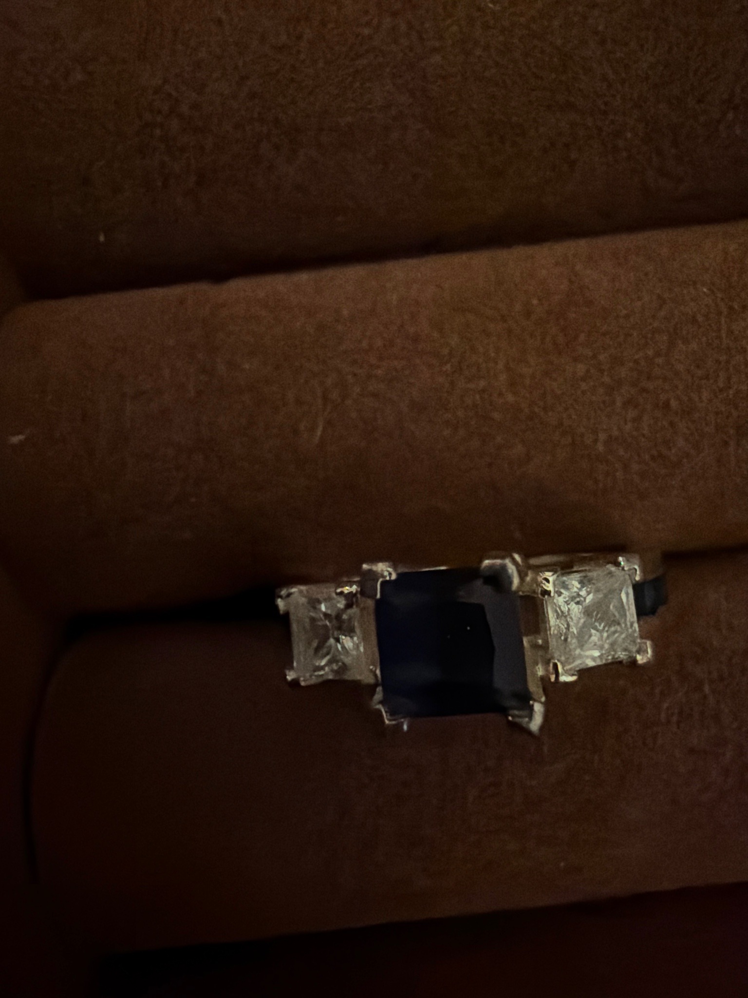 Submitted photo of Three-stone ring with dark center gemstone and side diamonds